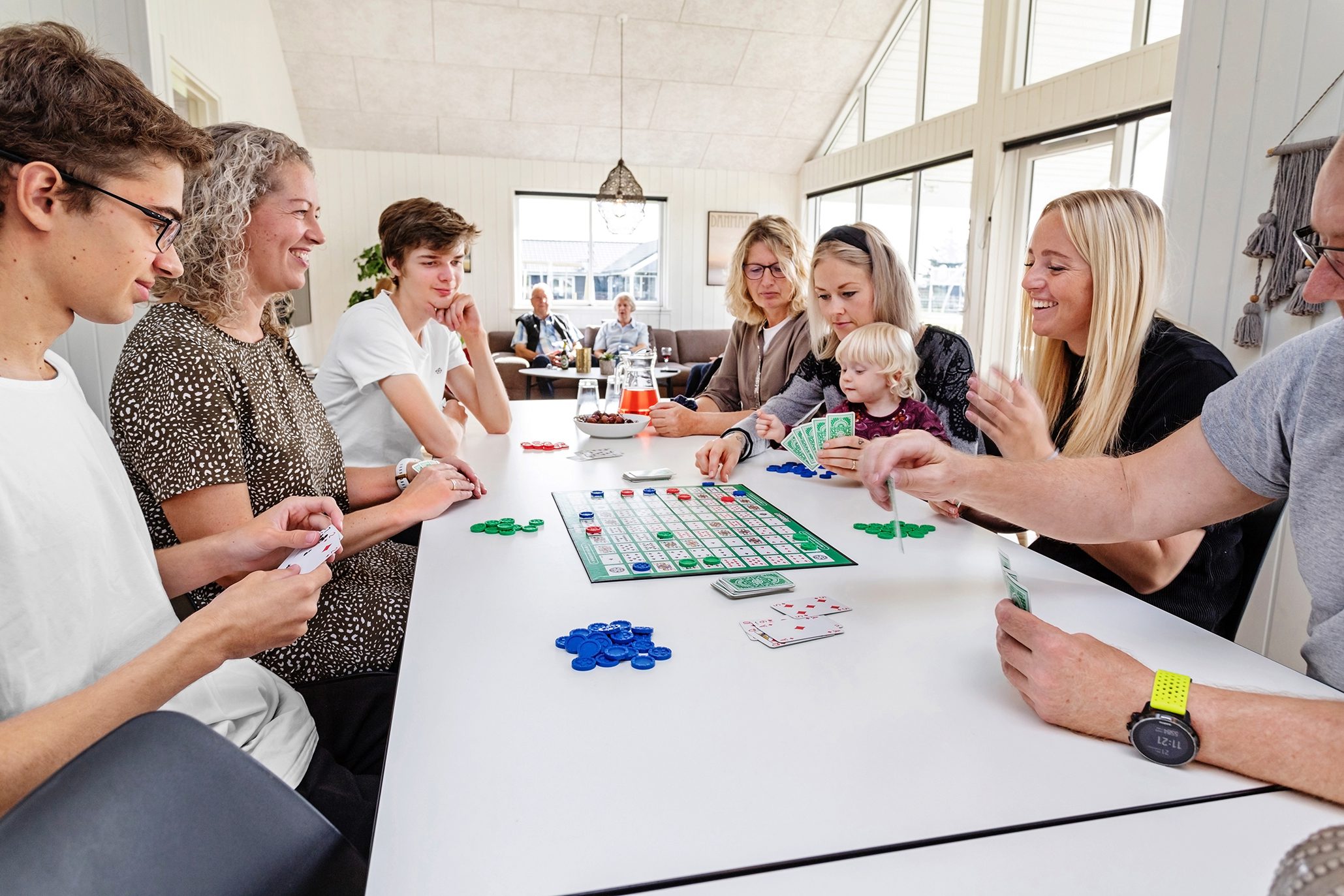 Familj som spelar brädspel i sommarstugans aktivitetsrum.