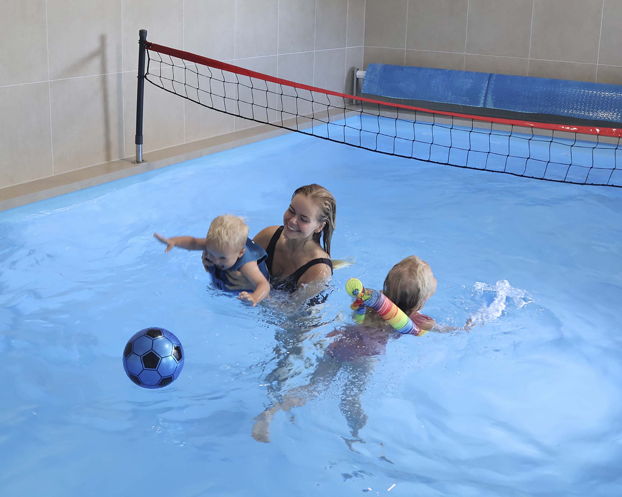 Barn som badar och leker i en stor inomhuspool
